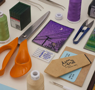 All the essential tools required for machine embroidery, including a sewing machine, embroidery hoops, threads, stabilizers, and fabric, displayed neatly for a comprehensive guide on machine embroidery.