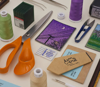 All the essential tools required for machine embroidery, including a sewing machine, embroidery hoops, threads, stabilizers, and fabric, displayed neatly for a comprehensive guide on machine embroidery.