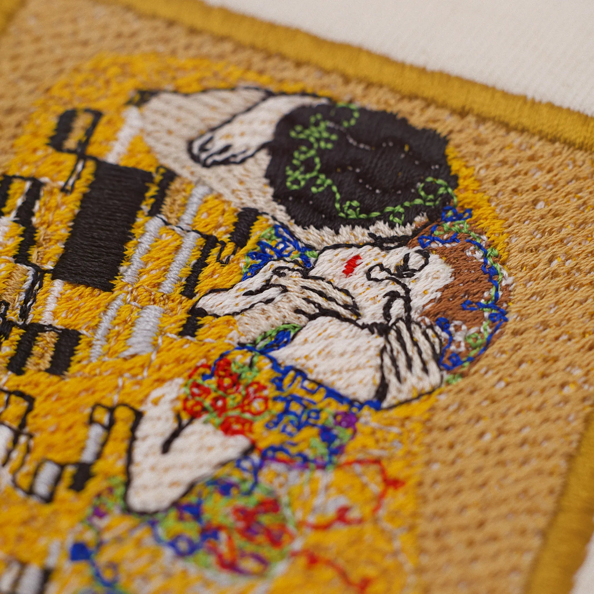Close-up of The Kiss embroidery after Klimt: gold areas, satin edges and colorful ornaments