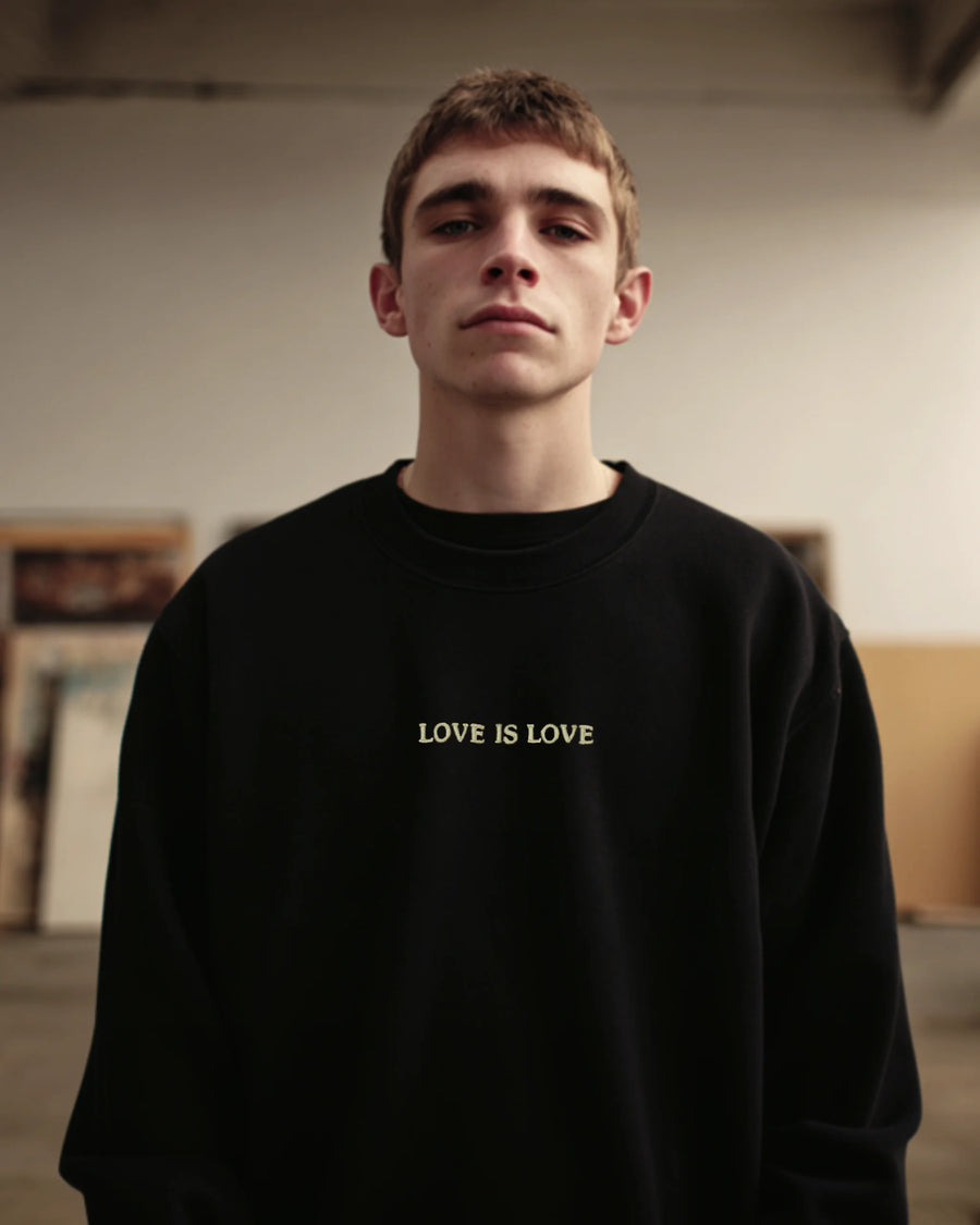 Schwarzes besticktes Sweatshirt mit Statement-Schriftzug auf der Brust, getragen von Model in minimalistischer Portraitaufnahme